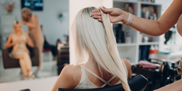 A woman having her hair checked by a hair stylist near me