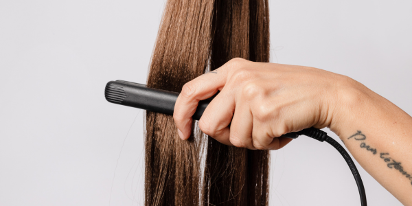 A woman having her hair straightened by a hair stylist near me