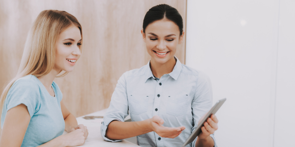 A receptionist showing a woman how to use an online booking system