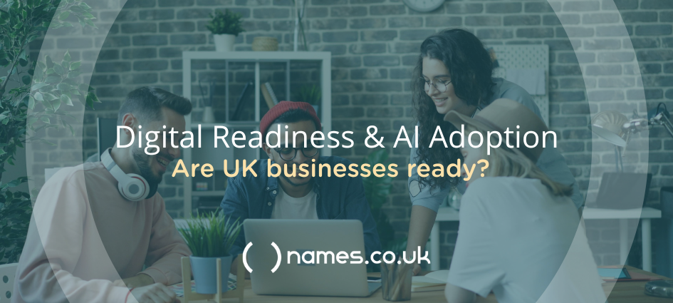 A group of smiling people clustered around a table looking at an open laptop.